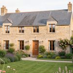 Maison familiale traditionnelle en pierre à Carhaix-Plouguer, entourée d’un jardin verdoyant sous une lumière douce de Bretagne.